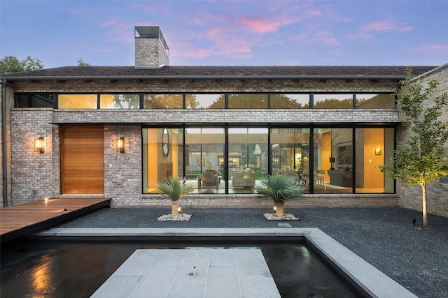 back house at dusk featuring a swimming pool