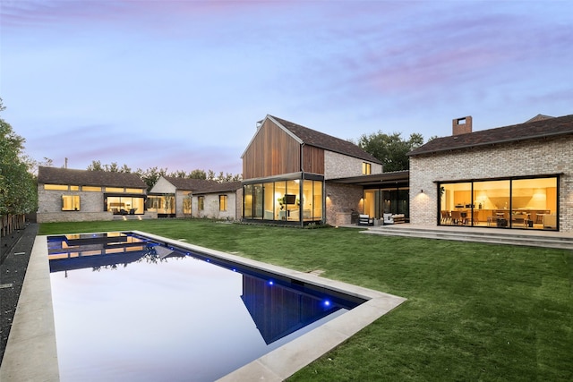 pool at dusk with a yard, a patio, and an outdoor pool