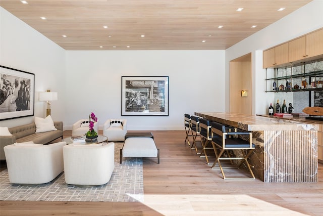 living room with wood ceiling, indoor bar, and light hardwood / wood-style flooring