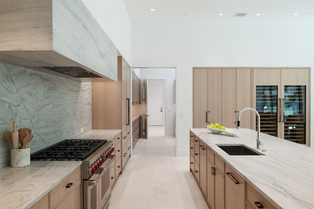 kitchen with premium range hood, light stone counters, sink, double oven range, and a high ceiling