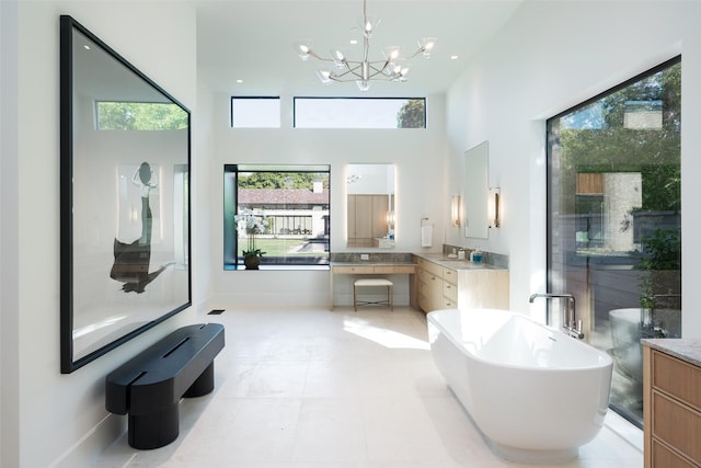 bathroom with vanity, a bathtub, an inviting chandelier, tile patterned floors, and a towering ceiling