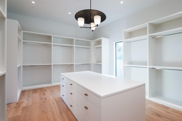 spacious closet with a chandelier and light hardwood / wood-style flooring