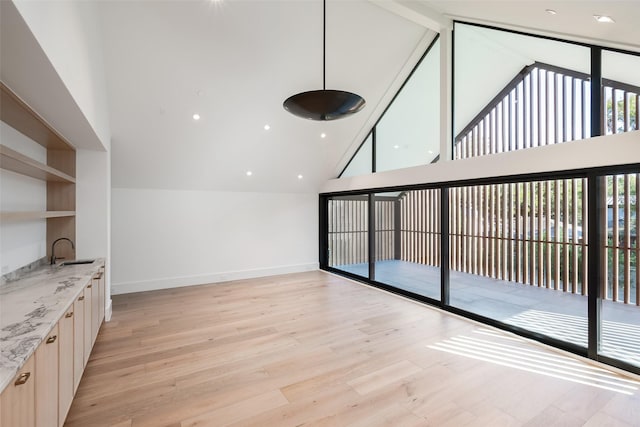 unfurnished living room featuring light hardwood / wood-style flooring, lofted ceiling, and sink