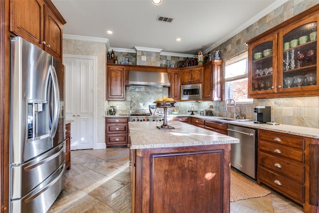 kitchen featuring a kitchen island, stainless steel appliances, wall chimney range hood, and ornamental molding