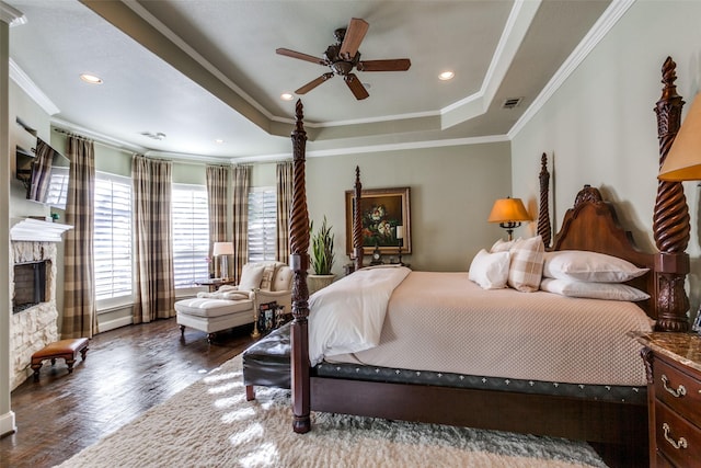 bedroom with a fireplace, a raised ceiling, ceiling fan, hardwood / wood-style flooring, and ornamental molding