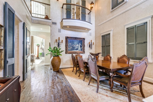 dining area with a towering ceiling and light wood-type flooring