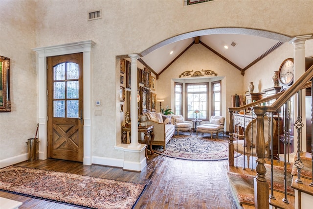 entryway with dark hardwood / wood-style flooring, crown molding, and ornate columns