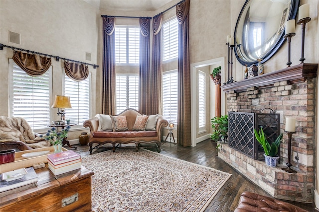 living room featuring a high ceiling, dark hardwood / wood-style flooring, and a fireplace