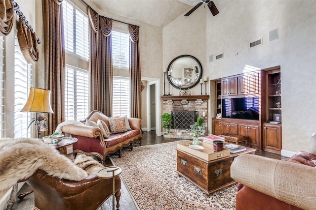 living room featuring a high ceiling, ceiling fan, a fireplace, and wood-type flooring