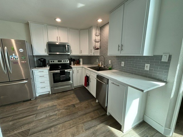 kitchen with stainless steel appliances, white cabinetry, tasteful backsplash, and sink