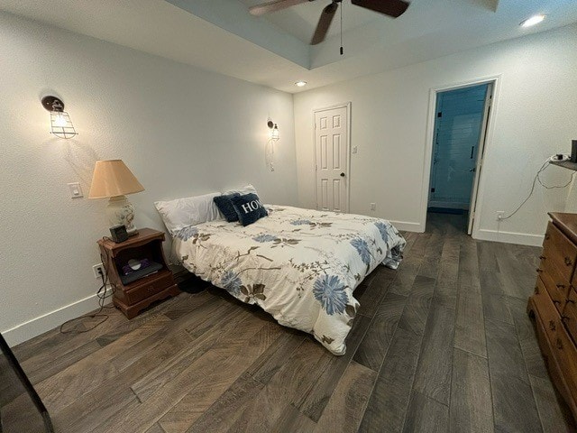 bedroom with dark hardwood / wood-style flooring, a raised ceiling, and ceiling fan