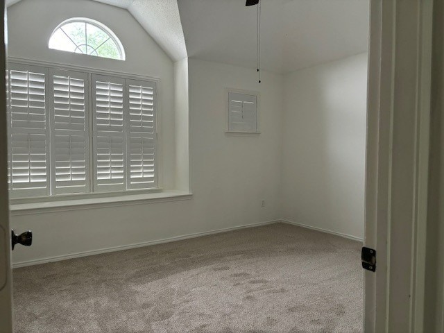 carpeted empty room featuring a textured ceiling and vaulted ceiling