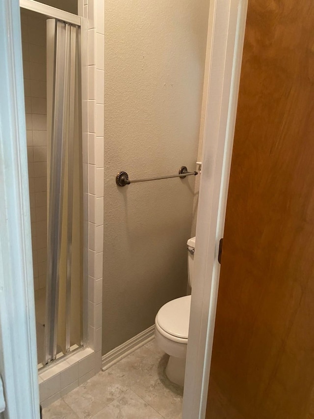 bathroom featuring toilet and a shower with door