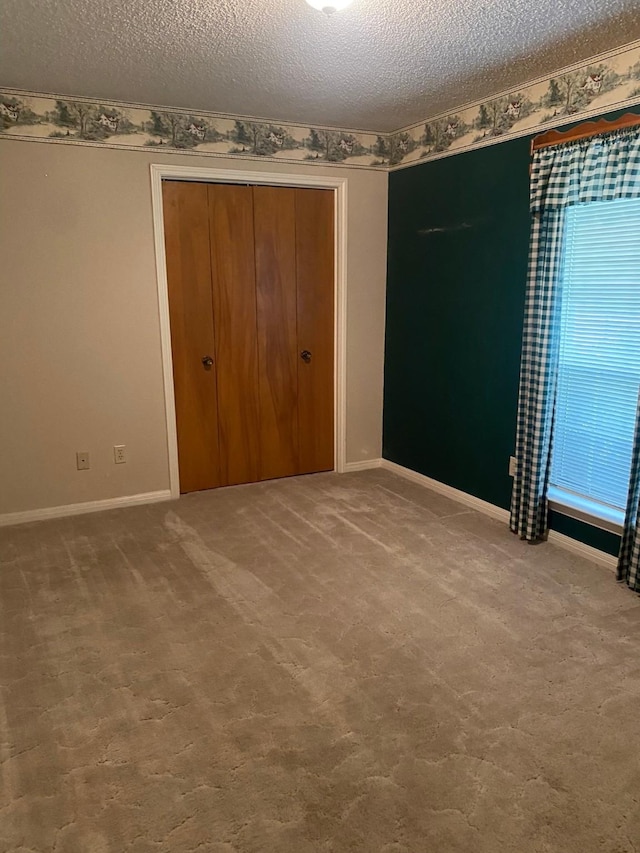 unfurnished bedroom featuring carpet, a textured ceiling, and a closet