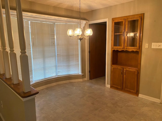 unfurnished dining area with a textured ceiling and an inviting chandelier