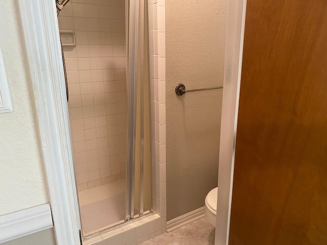 bathroom featuring a shower with door and toilet