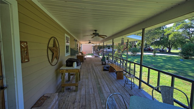 wooden terrace with a lawn, ceiling fan, and covered porch