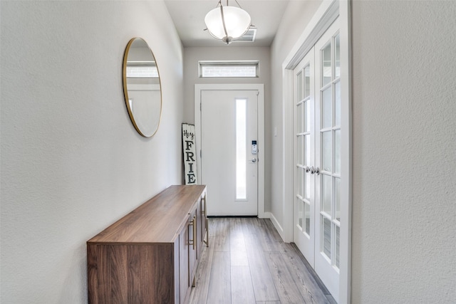 foyer featuring a wealth of natural light, french doors, and light hardwood / wood-style floors