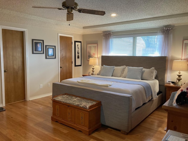 bedroom featuring ceiling fan, light hardwood / wood-style floors, and a textured ceiling