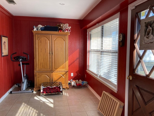 doorway featuring light tile patterned floors, radiator heating unit, and wooden walls