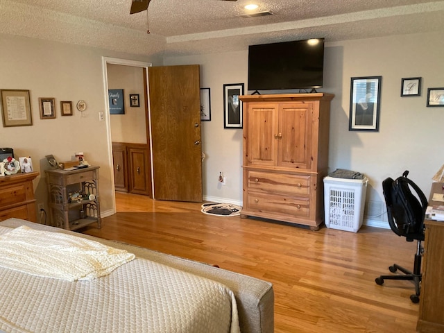 bedroom with a textured ceiling, light hardwood / wood-style flooring, and ceiling fan