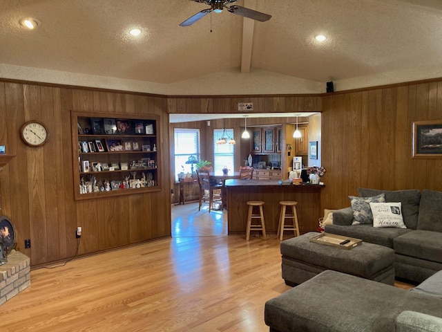 living room featuring built in shelves, wooden walls, and a textured ceiling