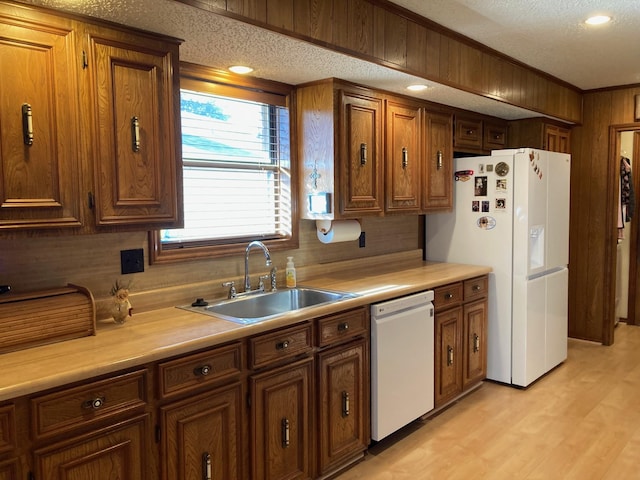 kitchen featuring a textured ceiling, sink, light hardwood / wood-style floors, and white appliances