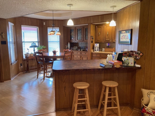 kitchen with wood walls, a breakfast bar, decorative light fixtures, and a textured ceiling