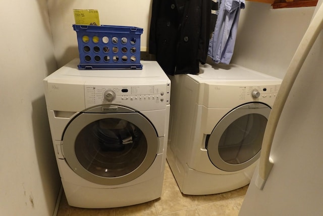 clothes washing area featuring light tile patterned floors and washer and dryer