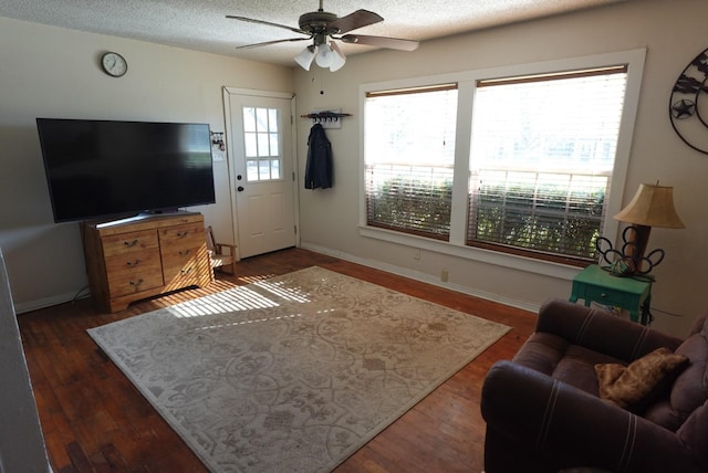 living room featuring ceiling fan, dark wood-type flooring, and a textured ceiling