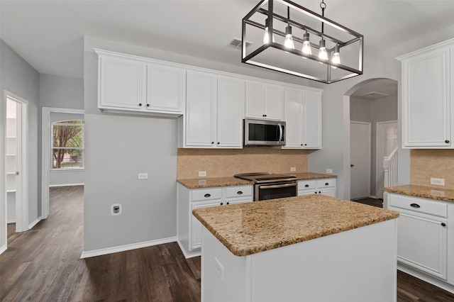 kitchen with white cabinets, decorative light fixtures, a kitchen island, light stone counters, and stainless steel appliances