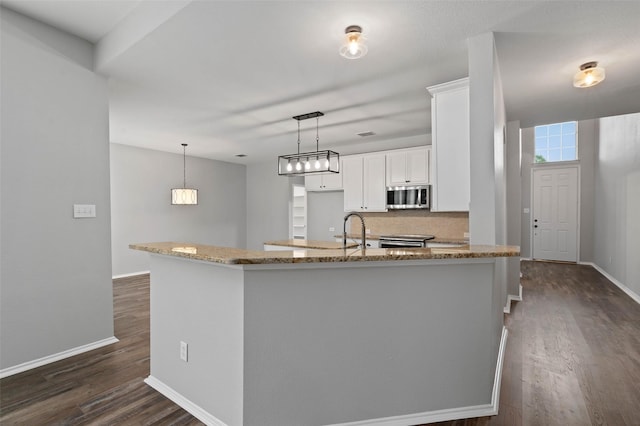 kitchen with backsplash, light stone counters, stainless steel appliances, decorative light fixtures, and white cabinets