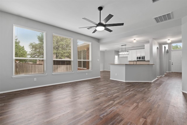 unfurnished living room featuring ceiling fan and dark hardwood / wood-style floors