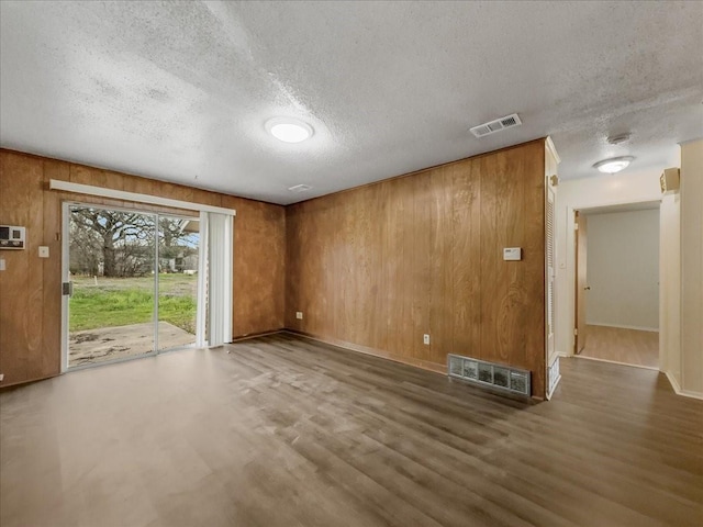 unfurnished living room featuring wood-type flooring, a textured ceiling, and wood walls