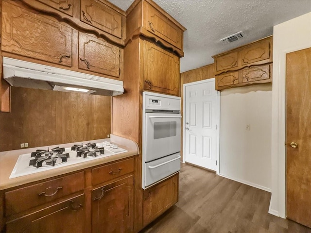 kitchen featuring white appliances, dark hardwood / wood-style floors, and a textured ceiling