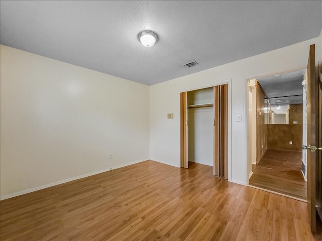 unfurnished bedroom with a closet, light hardwood / wood-style flooring, and a textured ceiling