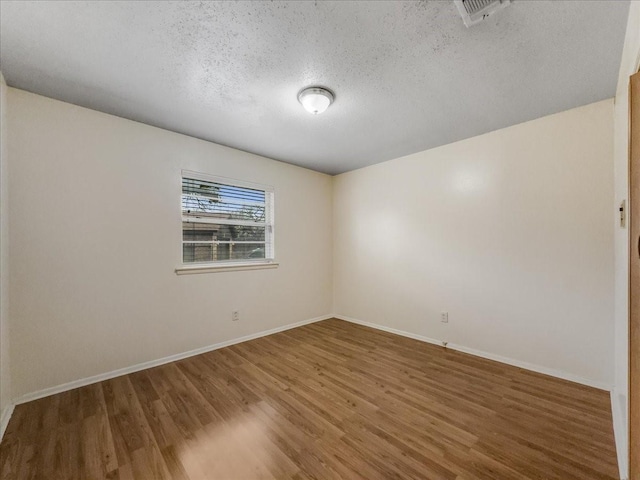 empty room featuring wood-type flooring and a textured ceiling