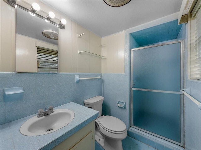 bathroom with an enclosed shower, vanity, tile walls, and toilet