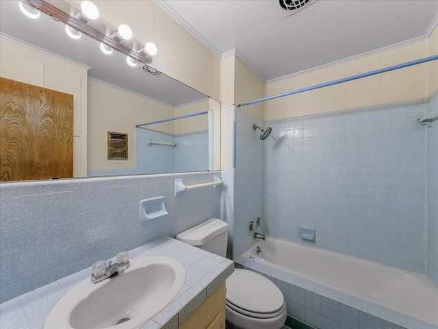 full bathroom with tile walls, tiled shower / bath combo, vanity, toilet, and crown molding