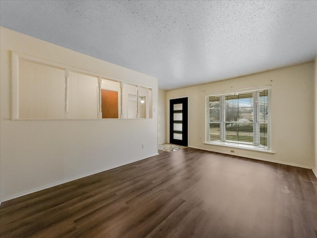 empty room with dark wood-type flooring and a textured ceiling