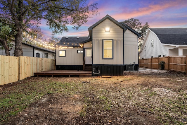 back house at dusk with cooling unit and a wooden deck