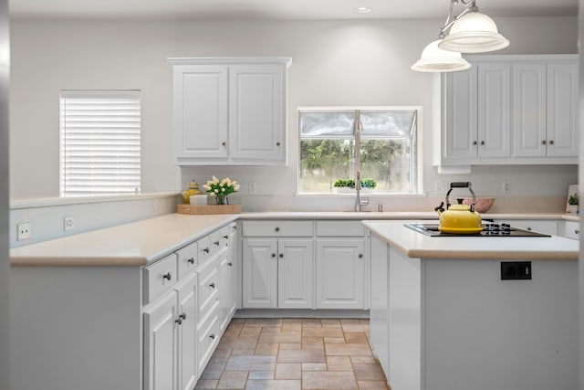 kitchen featuring black electric stovetop, sink, decorative light fixtures, white cabinets, and a kitchen island