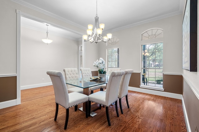 dining space featuring hardwood / wood-style floors, an inviting chandelier, and crown molding