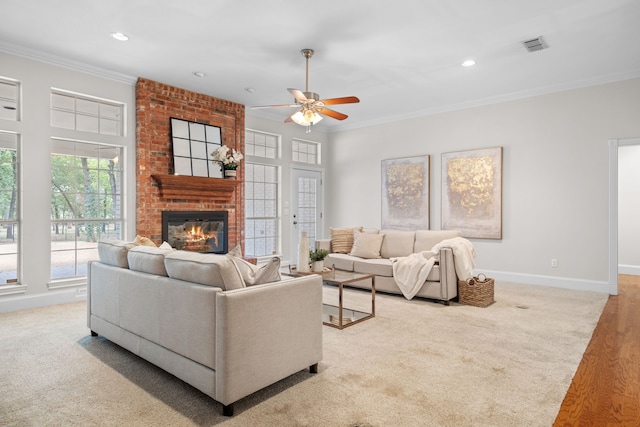 carpeted living room with ceiling fan, a fireplace, and crown molding