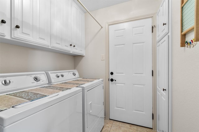 laundry area featuring light tile patterned floors, cabinets, and washing machine and clothes dryer