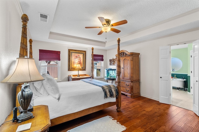 bedroom featuring hardwood / wood-style flooring, ensuite bath, a raised ceiling, and ceiling fan