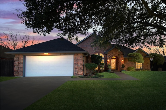 ranch-style house featuring a garage and a lawn