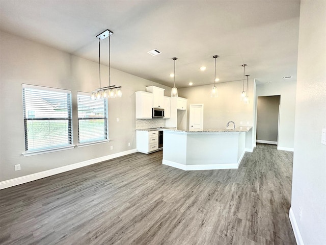 kitchen with light stone counters, hardwood / wood-style flooring, pendant lighting, white cabinets, and appliances with stainless steel finishes