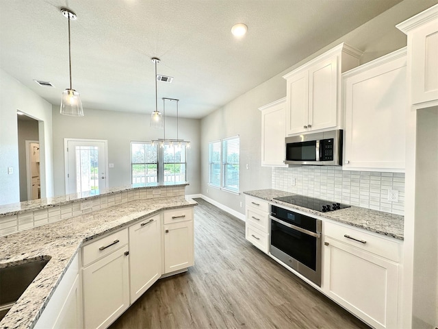 kitchen featuring hardwood / wood-style flooring, pendant lighting, tasteful backsplash, white cabinets, and appliances with stainless steel finishes