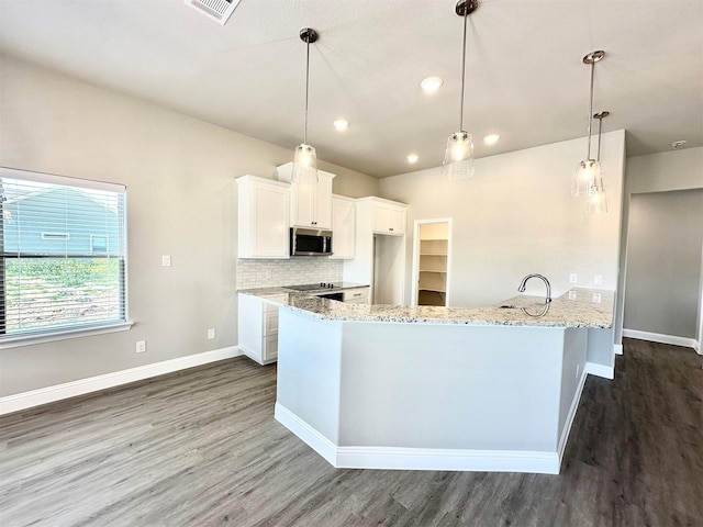 kitchen with decorative light fixtures, white cabinets, light stone countertops, and backsplash